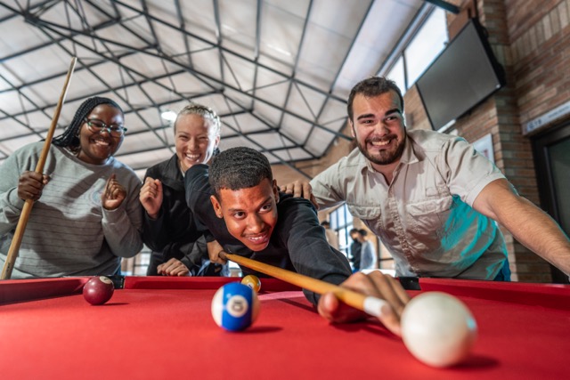 Group of undergrads playing on the pool table