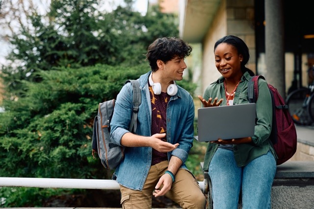 Male and female discussing and carrying a laptop
