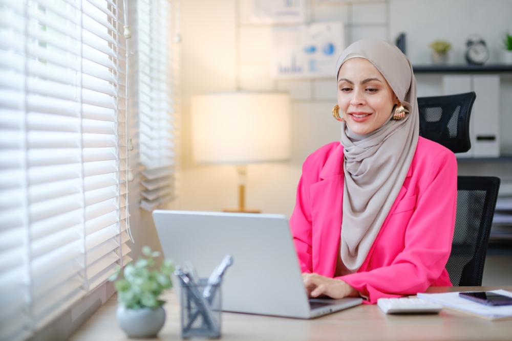 Woman wearing a pink blazer on her laptop