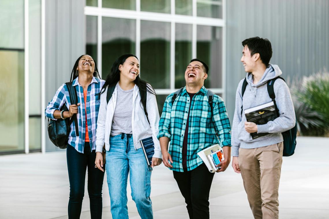 Four university students walking and laughing