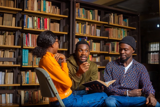 Three students sitting at the library talking