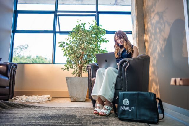 White girl sitting on couch working on laptop 