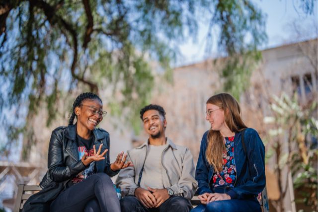 Three students sitting at Mahikeng campus conversating