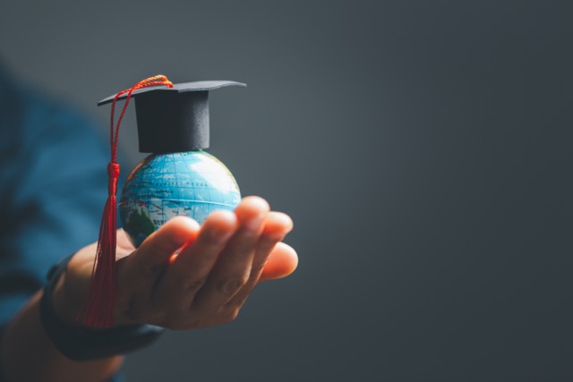 A person holding a world globe with a graduation hat