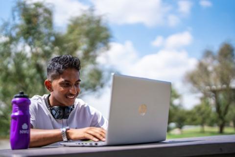 Indian Male sitting outside working on laptop