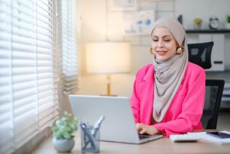 Woman wearing a pink blazer on her laptop