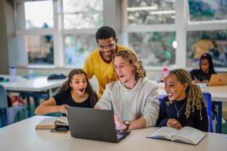 three students smiling at the laptop screen