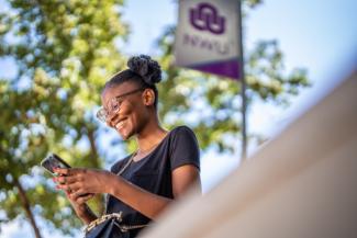 Female sitting outdoors, interacting with her phone