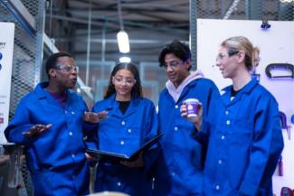 Four engineering students in blue overall jackets